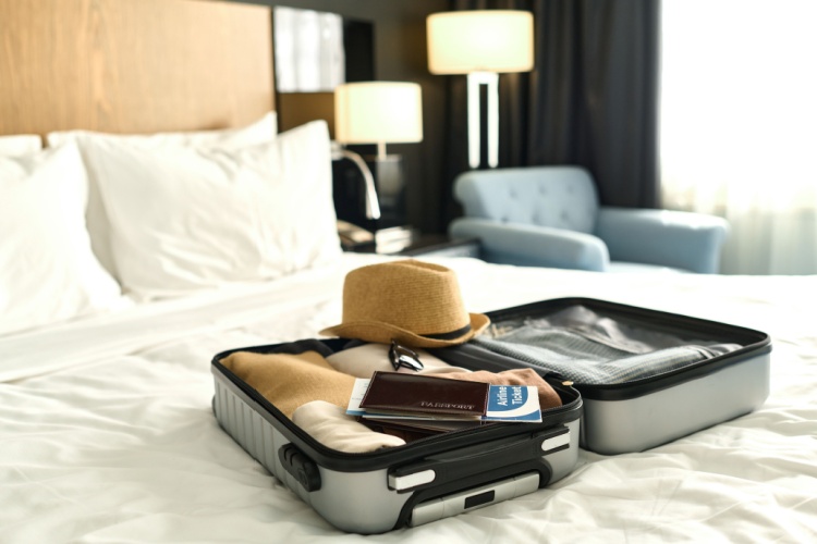 An open suitcase packed for a family vacation, with passport and tickets on top