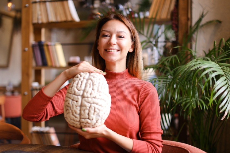 A smiling female psychologist holding a human brain model